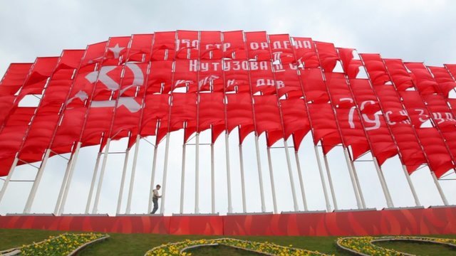 boy walks against huge communist red flags
