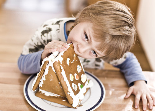 junge beisst in ein lebkuchen haus
