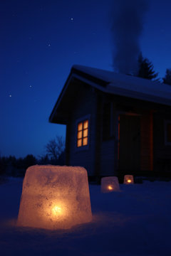 Log cabin in winter night with ice lantern decoration