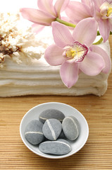Obraz na płótnie Canvas Spa essentials (bowl of stone, white towel and pink orchids)