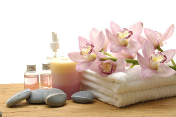 Spa essentials (cream, stones, white towel and pink orchids)