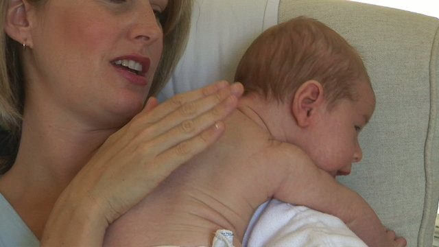 Mother burping newborn baby after the feeding