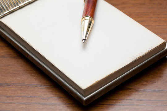 Elegant pen lying on a notebook on a wooden table