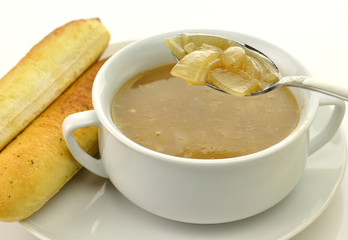 French Onion Soup in a white bowl with bread sticks