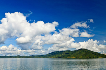 Big white clouds above a lake and mountains