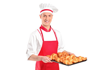 A baker with red apron holding croissants