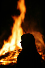 Eine junge Frau steht vor einem großen Feuer