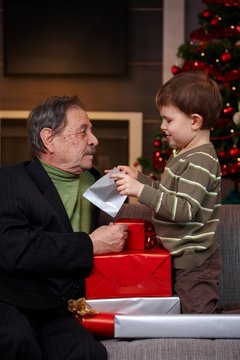 Small boy getting christmas present from grandfather