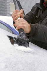 scraping snow and ice from the car windscreen