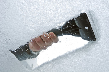 scraping snow and ice from the car windscreen