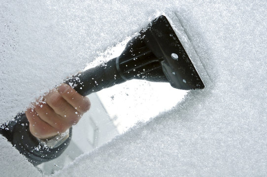 scraping snow and ice from the car windscreen