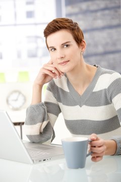 Young woman with coffee mug and laptop