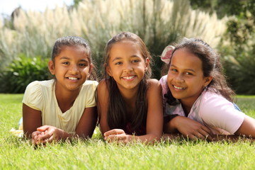 Three school girl friends lying in grass enjoying the sunshine