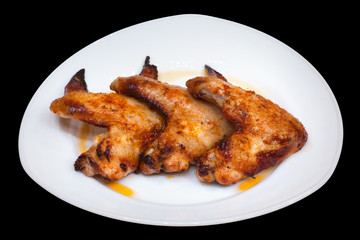 Cooked chicken wings on a plate isolated on black