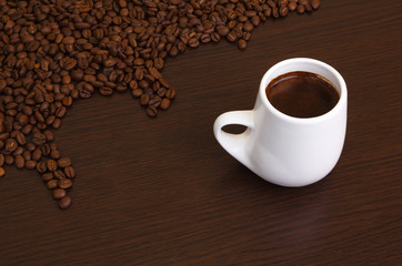 Coffee grains with a white cup on a brown background