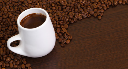 Coffee grains with a white cup on a brown background