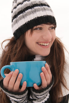 The girl smiles and holding a blue cup