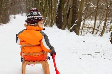 Kleinkind auf Holzschlitten