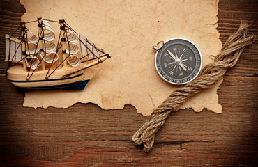 old paper, compass, rope and model classic boat on wood backgrou