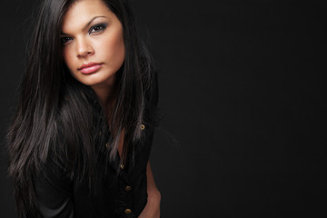 Fototapeta premium Brunette with long hair posing on black background.