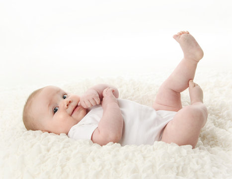 Baby lying on back with feet in the air and thumb in mouth