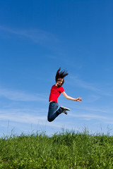 Girl jumping, running against blue sky