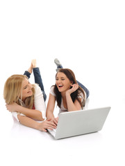 two Young pretty girl friends surfing in internet on laptop comp