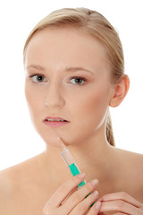 Young woman with syringe next to her lips