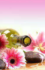 A spa composition of flowers, blue sky and an oil bottle