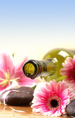 A spa composition of flowers, blue sky and an oil bottle