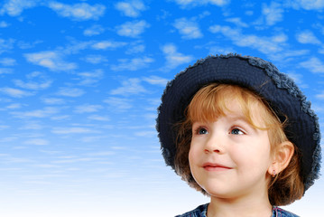 little girl with jeans hat and blue sky behind