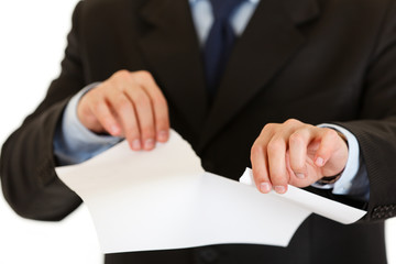 Businessman tearing sheet of white paper. Close-up.