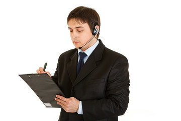 Serious young businessman with headset and clipboard