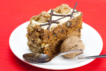 Piece of cake with nuts and spoon lying on a plate