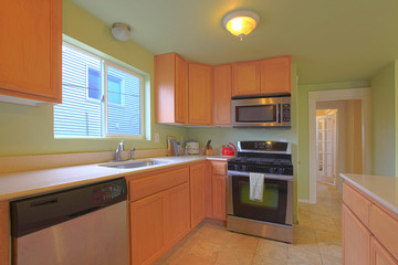 Green kitchen with maple cabinets and black appliances