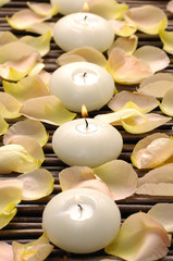 Row of candle and rose petals on mat