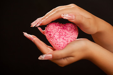 Human hands with beautiful manicure hold pink heart