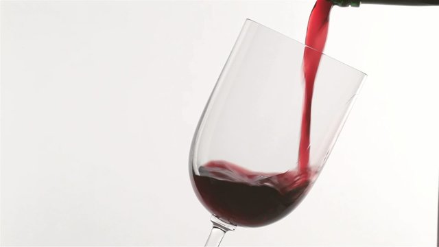 Rotwein wird in ein Glas eingeschenkt