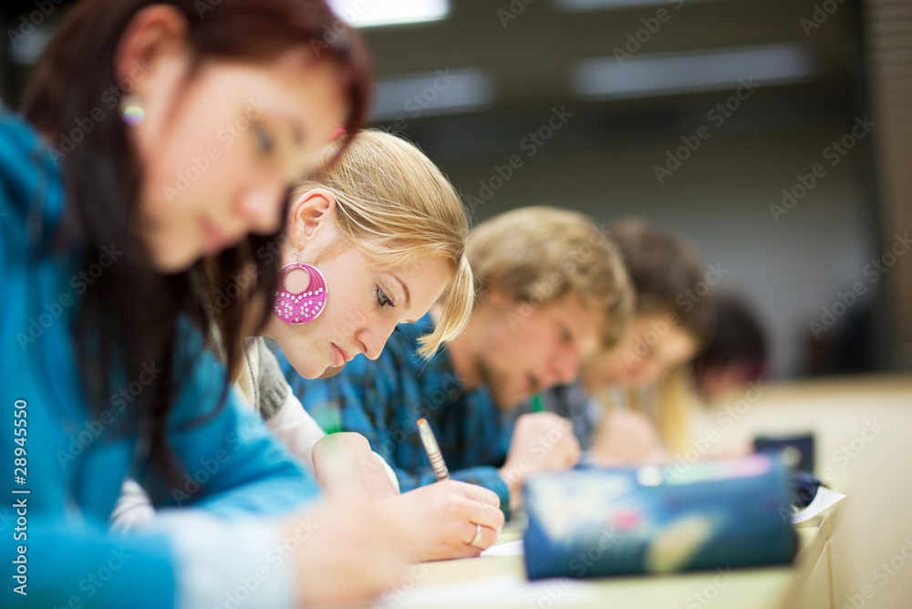 Wall mural pretty female college student sitting an exam in a classroom