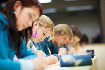 pretty female college student sitting an exam in a classroom