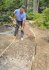 Man building gravel path with wood edging