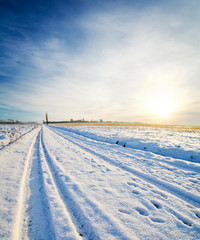 Fototapeta na wymiar rural road under snow. winter sunset