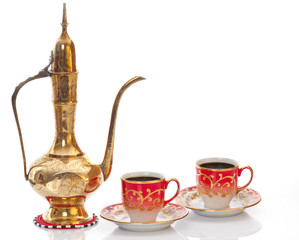 Arabic brass coffee pot with a welcoming  cups full of coffee.