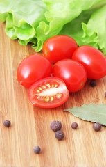 Ripe tomatoes, spices and salad sheet on a chopping board