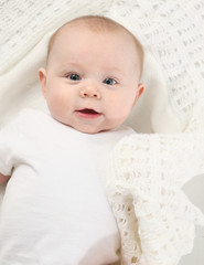 closeup portrait of adorable baby lying on a white blanket