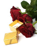 three red roses and golden ring in box