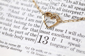 Gold necklace with heart on Bible open to 1st Corinthians 13