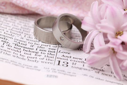 Titanium wedding rings on the Bible open to 1st Corinthians 13