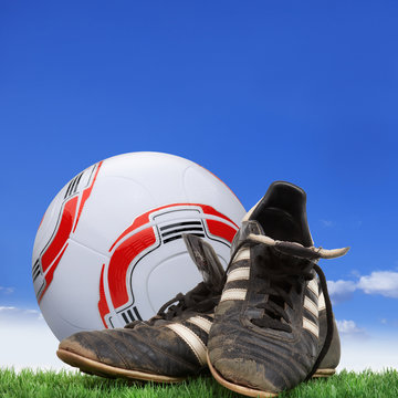 Bundesleague ball and soccer shoes on grass in front of sky