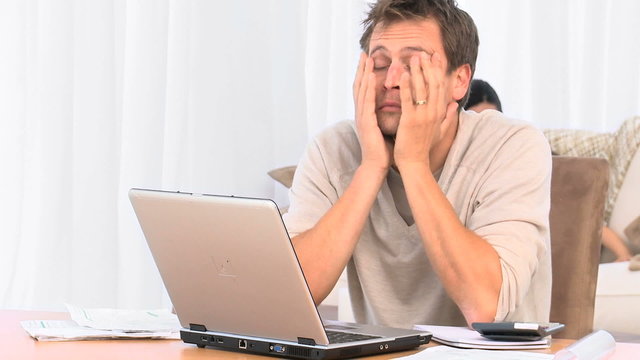 Annoyed guy calculating bills on the laptop